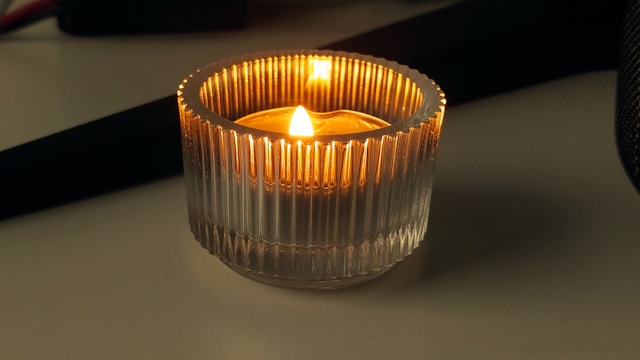 Lit candle in glass holder on table, symbolizing remembrance, cremation services Westmont, PA