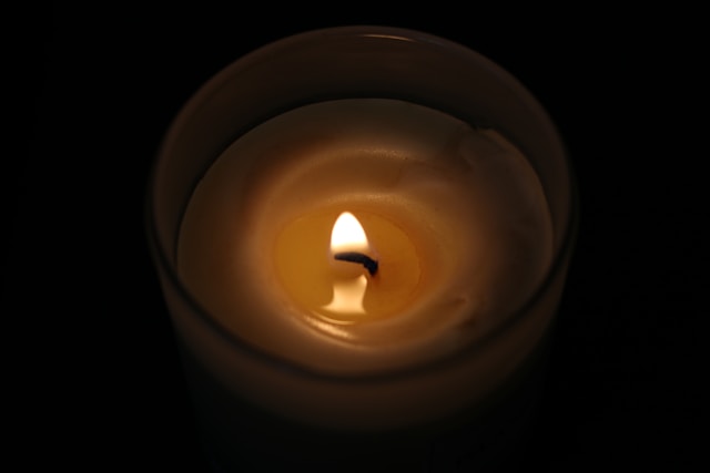 Thoughtful Care During Life’s Most Tender Moments Single lit candle in glass holder glowing in dark setting, symbolizing cremation services Johnstown, PA